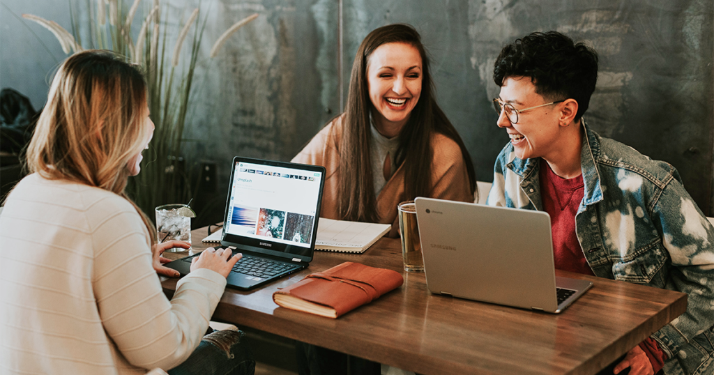 3 women working together in a café, laughing