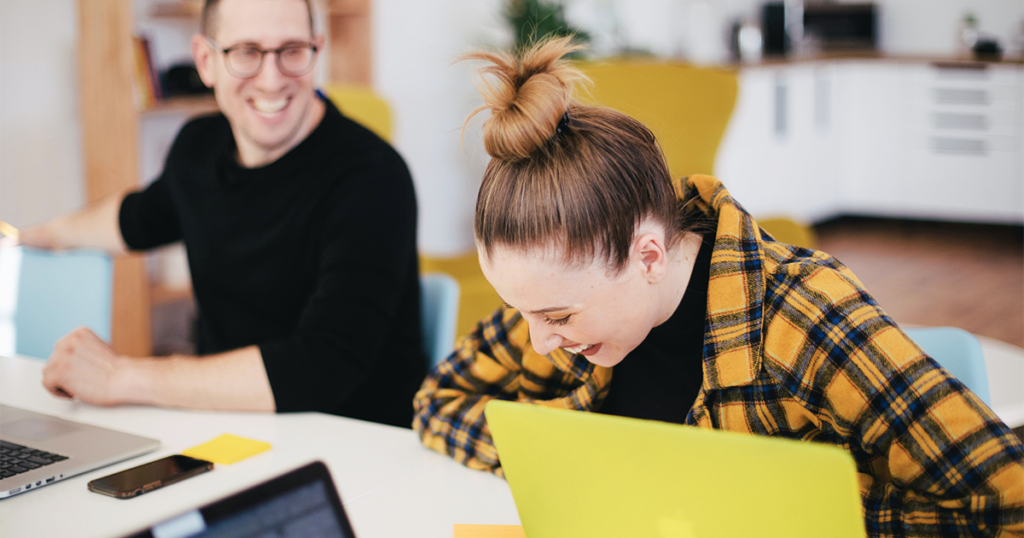 a women and man laughing, having a pleasant conversation at work during collaboration