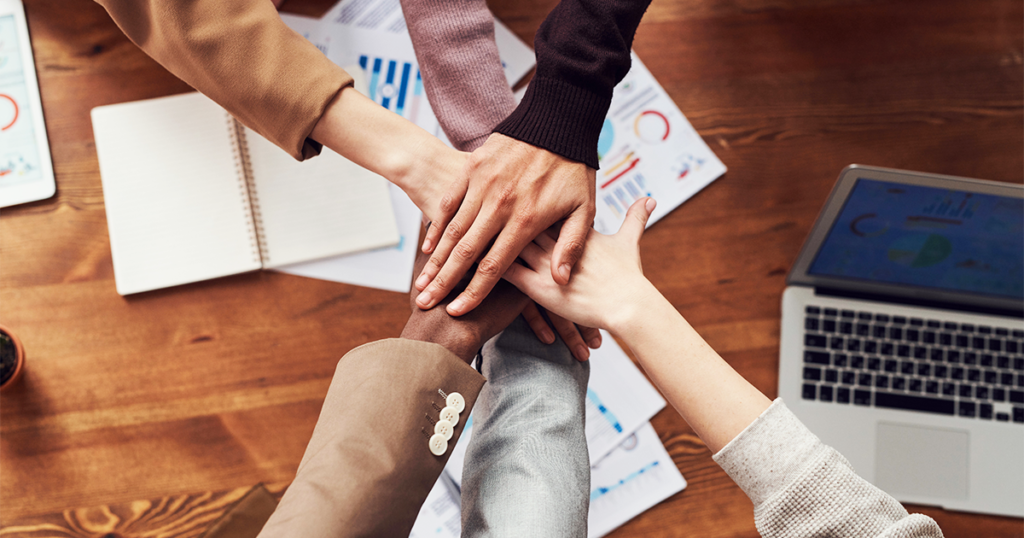 A team putting their hands in the middle to celebrate collaboration