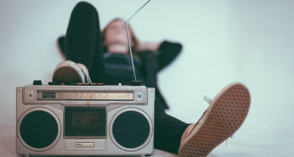 a boombox with someone resting their foot on the top while laying back on a wall