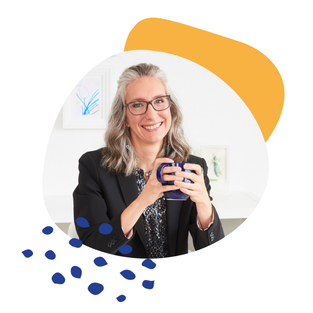 Picture of leadership speaker, Ginny Santos smiling while holding a blue mug