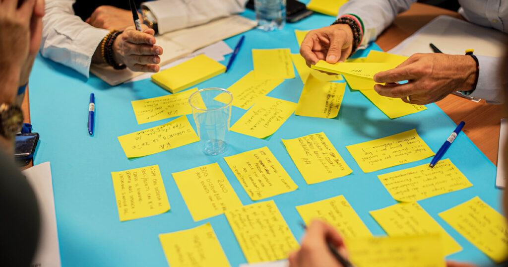 a group of people collaborating together, generating ideas on sticky notes