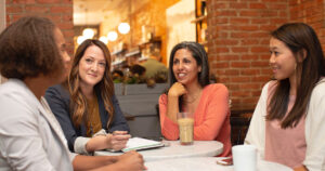 4 mature women sitting at a cafe collaborating, writing down ideas