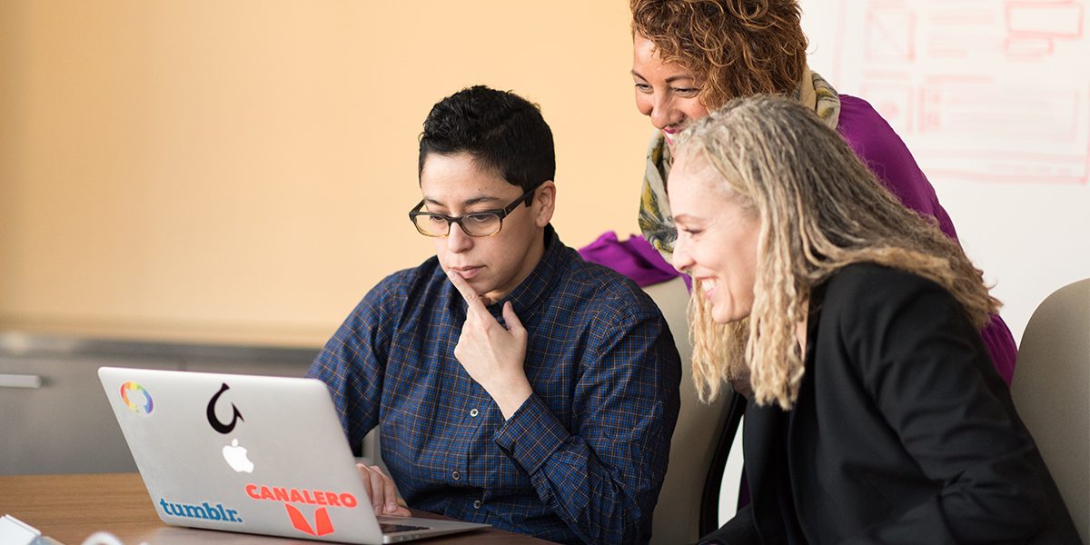 three people working on a problem together.